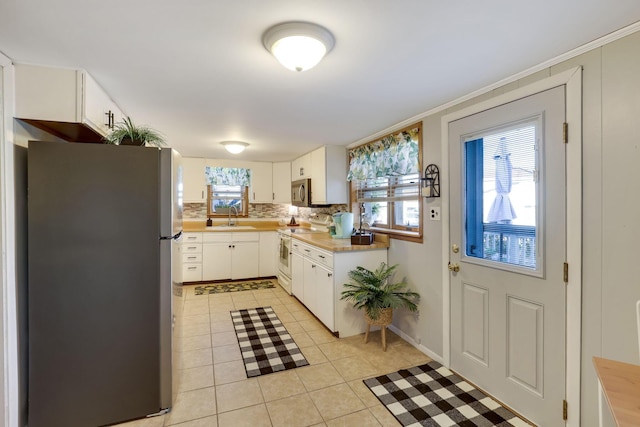 kitchen with sink, white cabinetry, stainless steel appliances, tasteful backsplash, and light tile patterned flooring