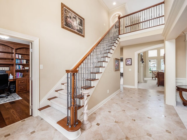 stairs with crown molding and a towering ceiling