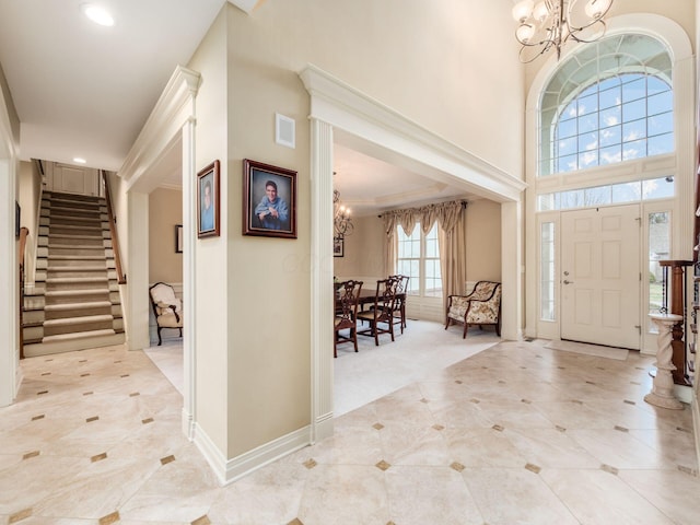 foyer featuring crown molding, a towering ceiling, light carpet, and a notable chandelier