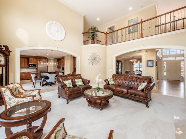 living room featuring an inviting chandelier, light colored carpet, ornamental molding, and a towering ceiling