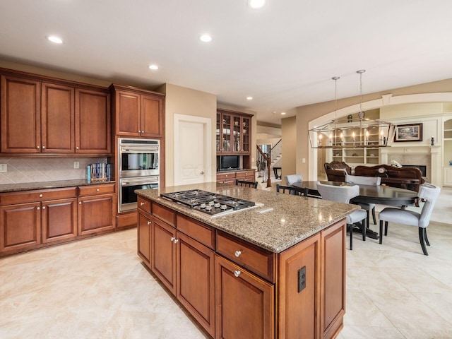 kitchen featuring stone counters, pendant lighting, decorative backsplash, a center island, and stainless steel appliances