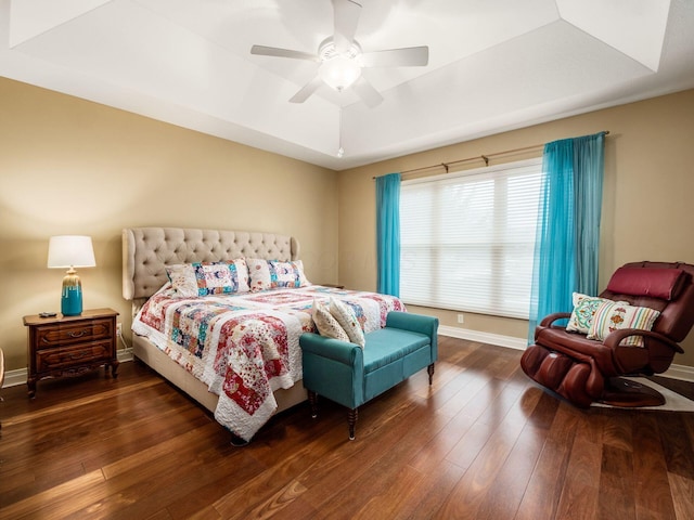 bedroom featuring dark wood-type flooring, a raised ceiling, and ceiling fan