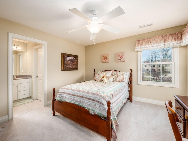 bedroom with ceiling fan, light colored carpet, sink, and ensuite bath