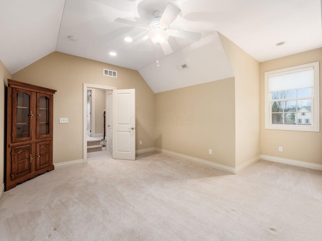 interior space with ceiling fan, light colored carpet, and vaulted ceiling