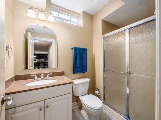 bathroom featuring tile patterned flooring, vanity, a shower with door, and toilet