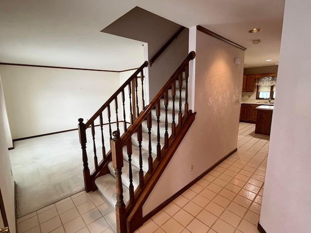 staircase featuring sink, tile patterned flooring, and ornamental molding