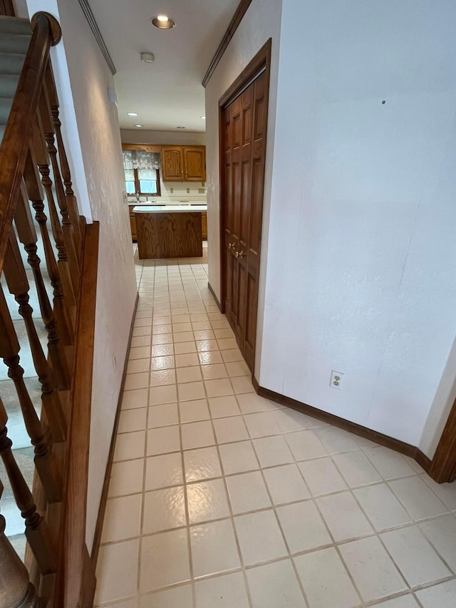 hallway with light tile patterned floors and ornamental molding