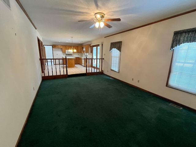 carpeted empty room featuring ceiling fan and ornamental molding