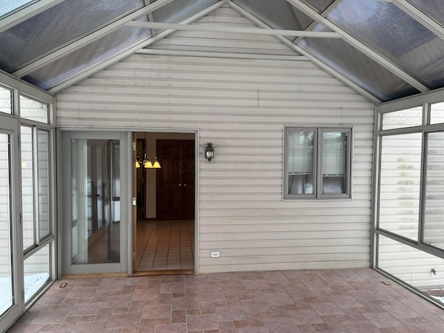 unfurnished sunroom with vaulted ceiling and a notable chandelier