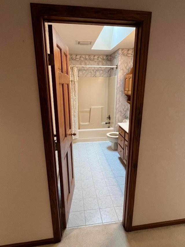 full bathroom with a skylight, tile patterned flooring, toilet, shower / washtub combination, and vanity