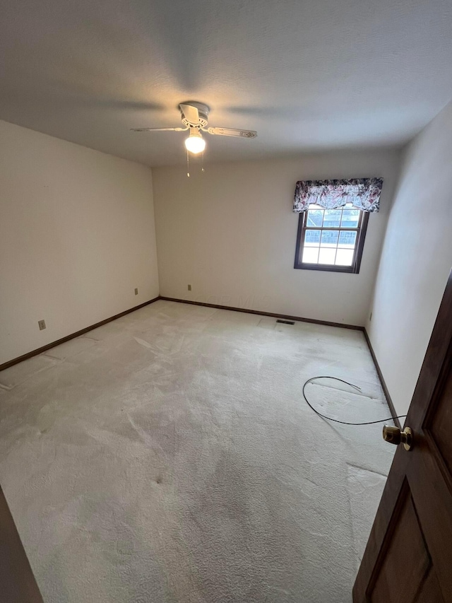 carpeted spare room featuring ceiling fan