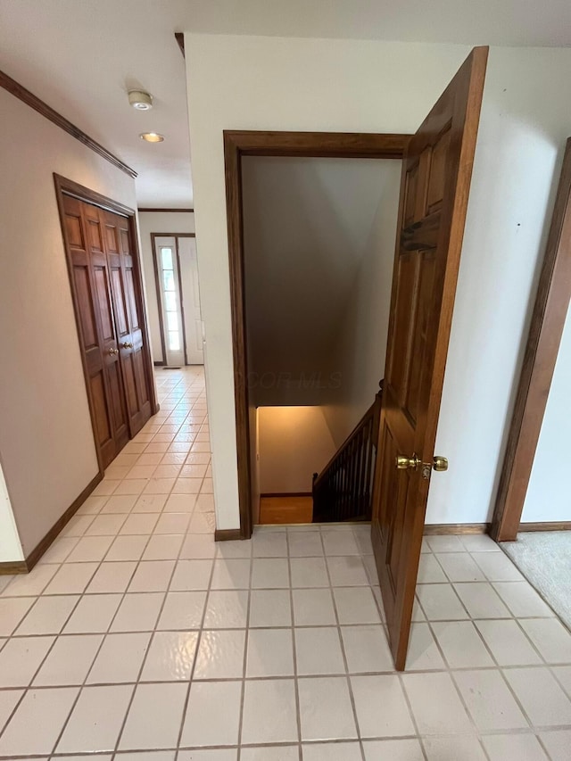 corridor featuring light tile patterned floors and crown molding