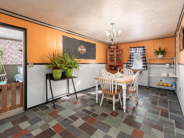 dining area with brick wall, a chandelier, and a textured ceiling