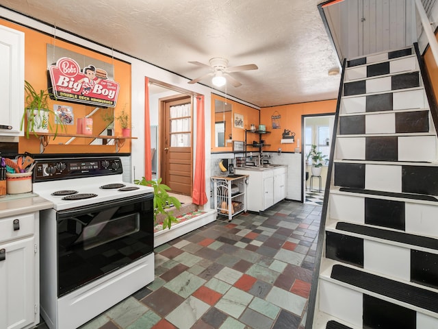 kitchen featuring a textured ceiling, ceiling fan, white cabinetry, and range with electric stovetop