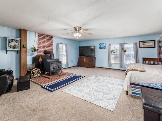 bedroom with ceiling fan, a wood stove, light colored carpet, and a textured ceiling