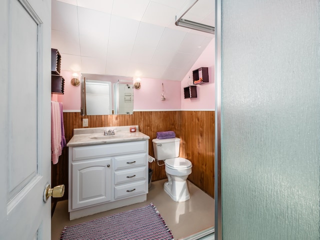 bathroom featuring vanity, toilet, wood walls, vaulted ceiling, and a shower with shower door