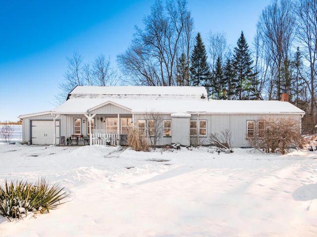 snow covered back of property with a garage