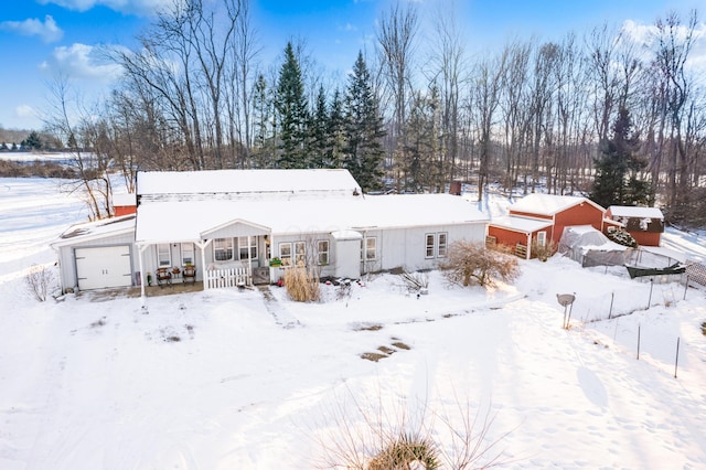 snow covered rear of property featuring a porch and a garage