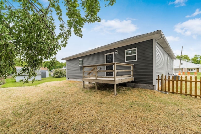 back of property with a yard, an outbuilding, and a deck