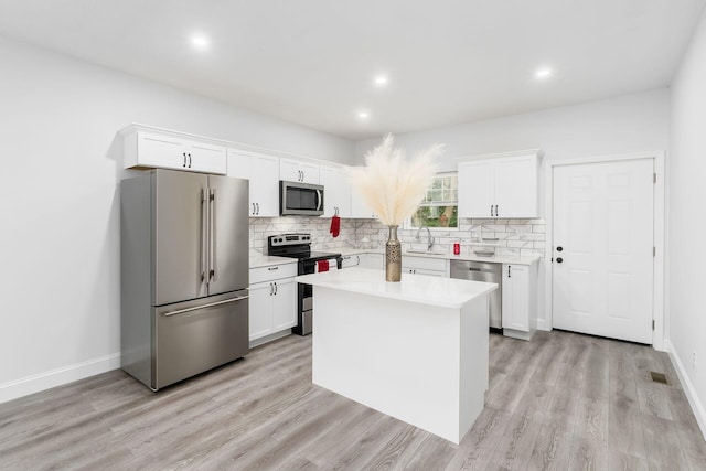 kitchen featuring white cabinets, a kitchen island, stainless steel appliances, and light hardwood / wood-style floors