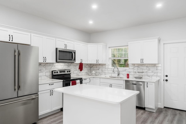 kitchen with a center island, white cabinets, sink, light hardwood / wood-style flooring, and appliances with stainless steel finishes