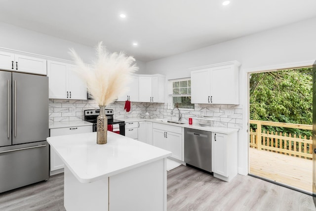 kitchen with white cabinetry, a center island, sink, backsplash, and appliances with stainless steel finishes