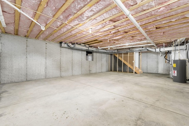 basement featuring electric water heater and brick wall