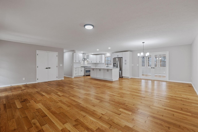 unfurnished living room with an inviting chandelier, sink, and light hardwood / wood-style floors