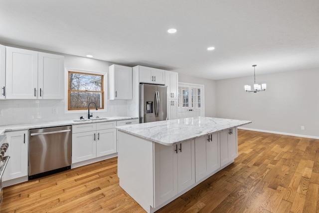 kitchen featuring stainless steel appliances, a kitchen island, sink, and white cabinets