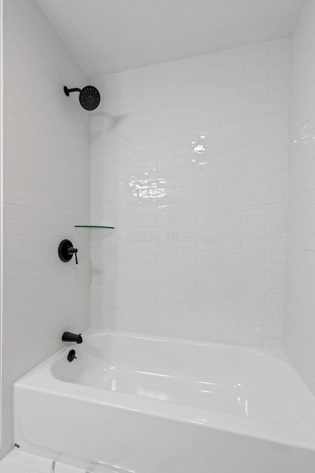 bathroom with tiled shower / bath and a textured ceiling