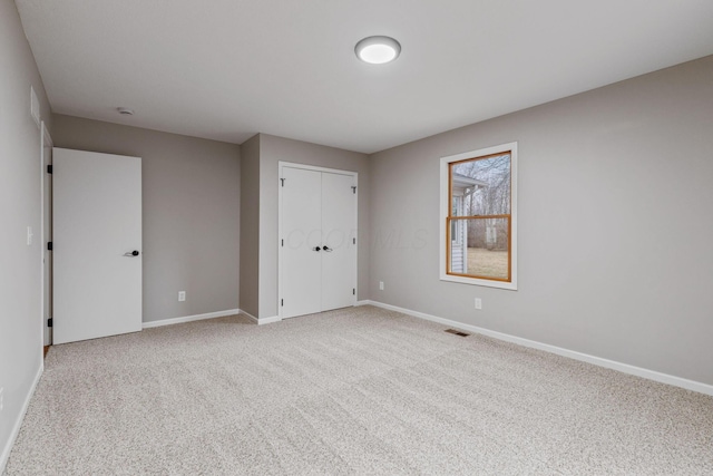 unfurnished bedroom featuring light carpet and a closet