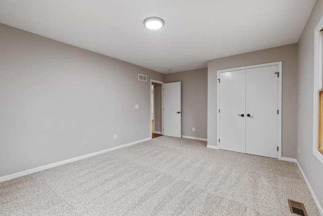 unfurnished bedroom featuring light carpet and a closet