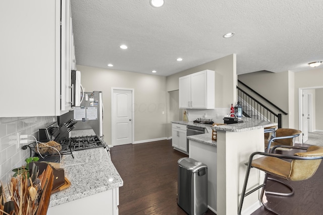 kitchen with white cabinets, a kitchen breakfast bar, decorative backsplash, light stone countertops, and kitchen peninsula