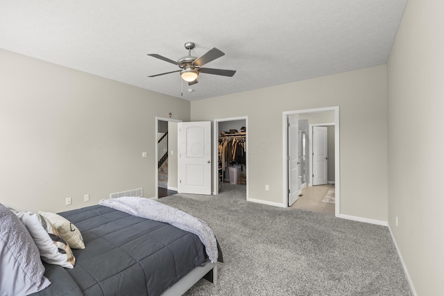 bedroom featuring a spacious closet, ceiling fan, a textured ceiling, light carpet, and a closet