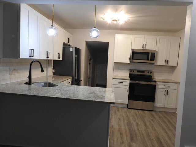 kitchen featuring decorative light fixtures, sink, white cabinets, and stainless steel appliances