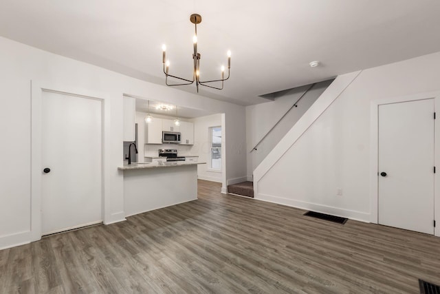 kitchen with white cabinetry, kitchen peninsula, stainless steel appliances, pendant lighting, and sink