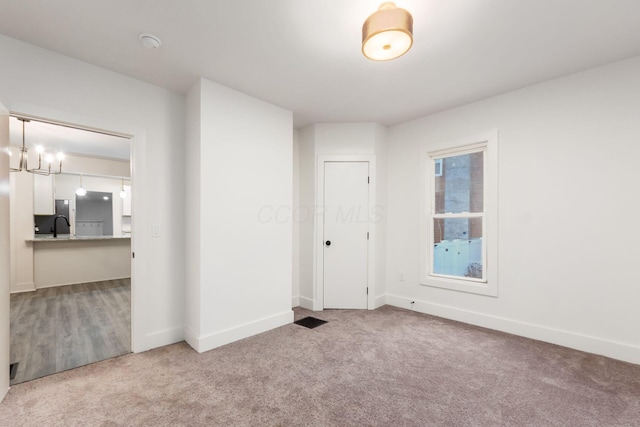 carpeted spare room featuring sink and a notable chandelier