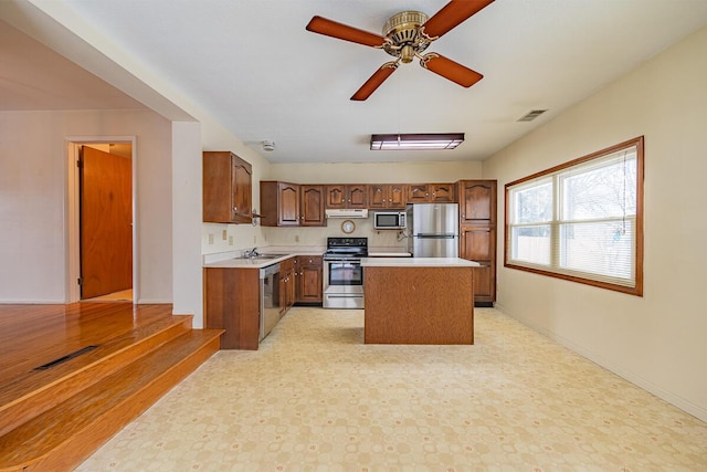 kitchen featuring ceiling fan, a kitchen island, sink, and stainless steel appliances