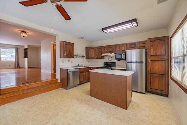 kitchen featuring ceiling fan, sink, a kitchen island, and stainless steel appliances