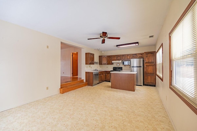 kitchen with ceiling fan, sink, a kitchen island, and appliances with stainless steel finishes