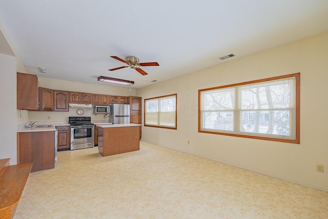 kitchen with sink, a center island, ceiling fan, and appliances with stainless steel finishes