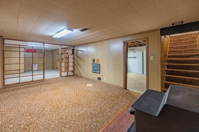 basement featuring carpet flooring and wood walls