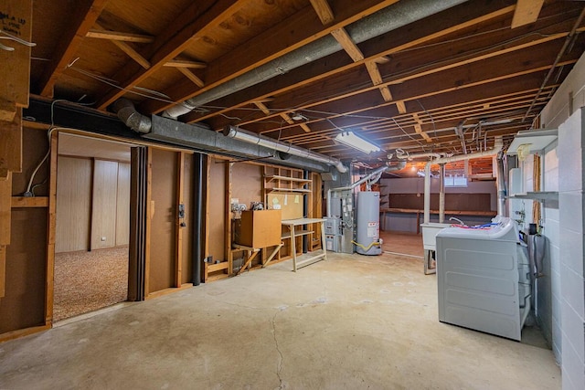 basement featuring independent washer and dryer, sink, and water heater