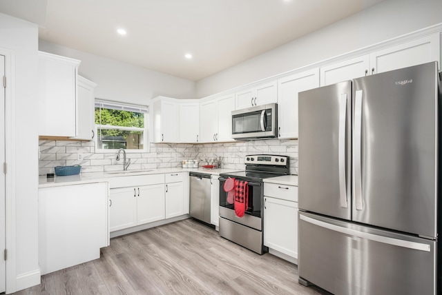 kitchen with white cabinetry, stainless steel appliances, sink, and backsplash