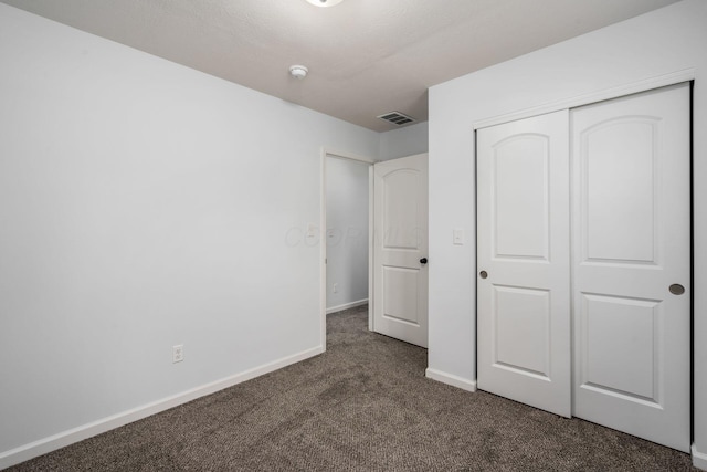 unfurnished bedroom with dark carpet and a closet