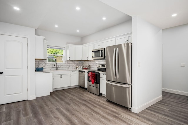 kitchen with sink, white cabinetry, backsplash, stainless steel appliances, and wood-type flooring