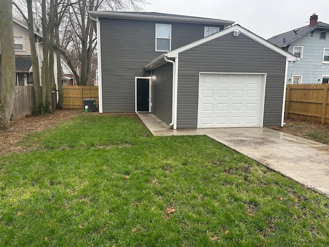 rear view of house featuring cooling unit, a garage, and a yard