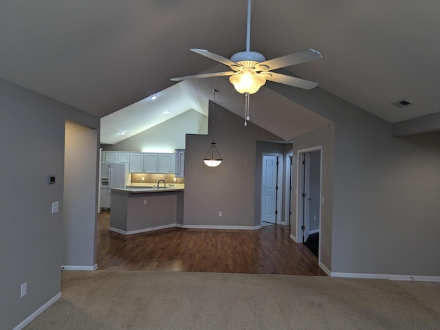 unfurnished living room with carpet flooring, ceiling fan, sink, and vaulted ceiling