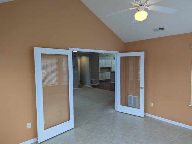 tiled empty room with ceiling fan, french doors, and lofted ceiling