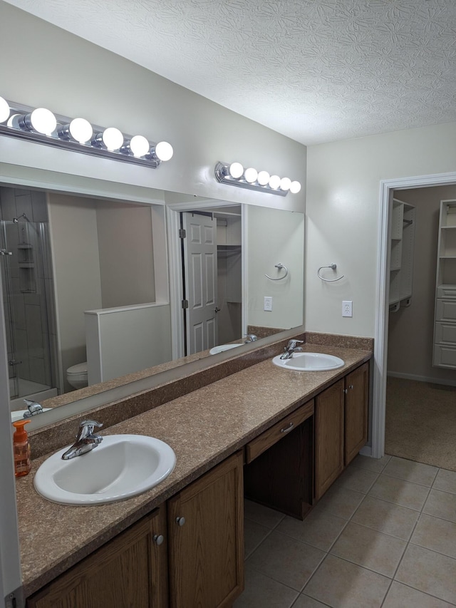 bathroom with vanity, tile patterned flooring, toilet, walk in shower, and a textured ceiling